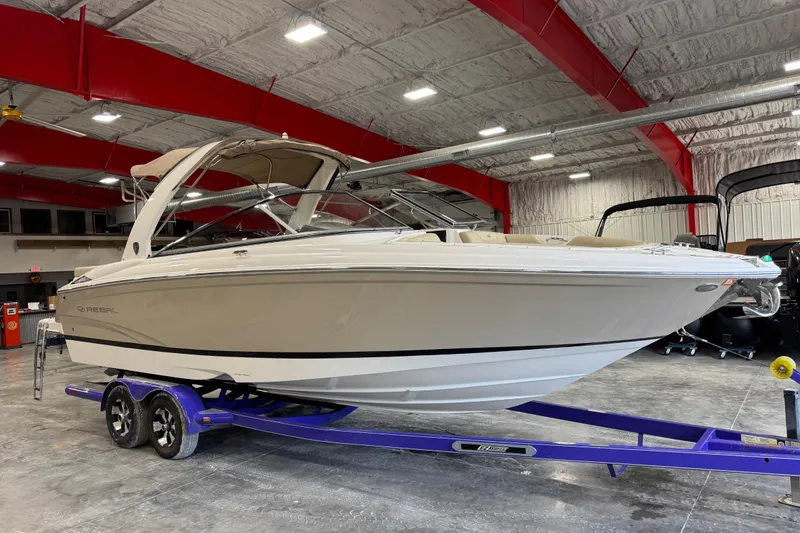 The Image of 2015 Regal 2700 Bowrider boat on a trailer in a spacious indoor facility. - 1
