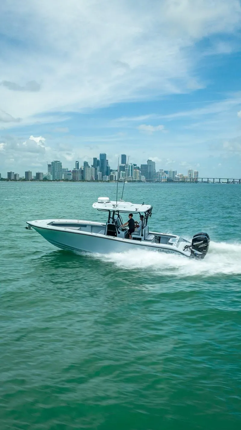 Slide: The Image of 2021 Yellowfin 29 Offshore boat cruising on water with city skyline. - 15