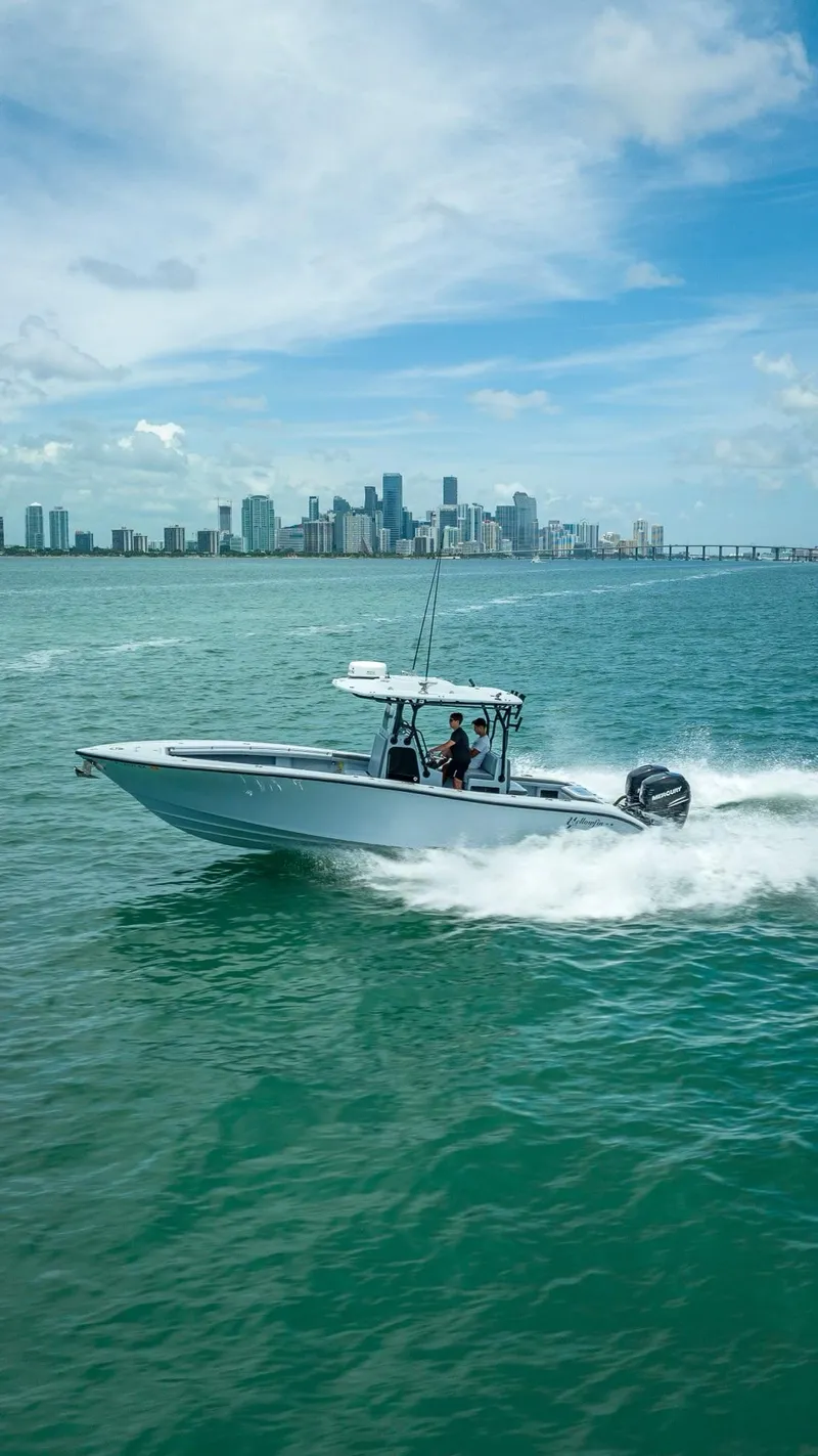 Slide: The Image of 2021 Yellowfin 29 Offshore boat cruising on water with city skyline. - 16