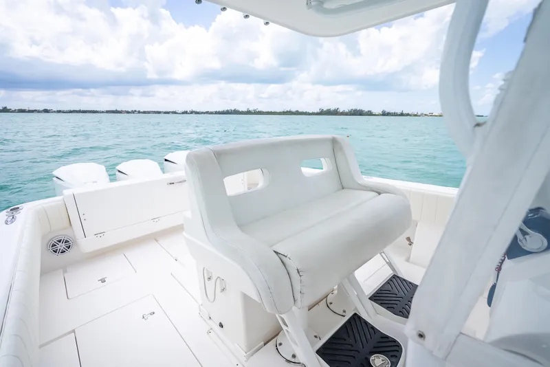 Slide: The Image of 2015 Intrepid 400 Cuddy boat interior with white seating, overlooking calm blue waters. - 23