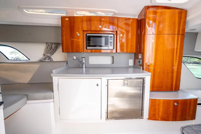 Slide: The Image of 2015 Intrepid 400 Cuddy interior with kitchenette, featuring wood cabinets and modern appliances. - 41
