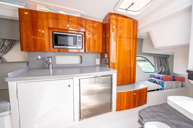 Slide: The Image of 2015 Intrepid 400 Cuddy interior with modern kitchenette, featuring wood cabinets and stainless steel appliances. - 43