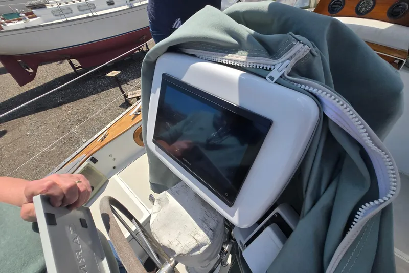 Slide: The Image of 1983 Bristol 38.8 sailboat cockpit with covered navigation equipment and steering wheel. - 28