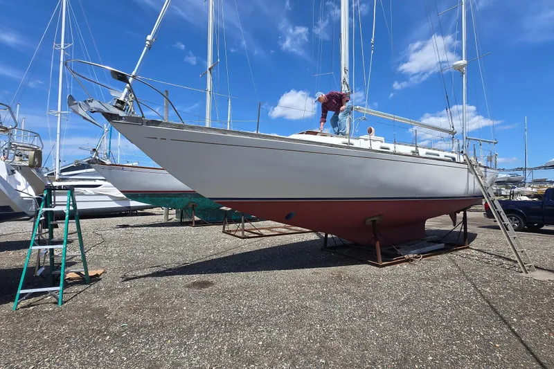 Slide: The Image of 1983 Bristol 38.8 sailboat on dry dock with person performing maintenance. - 30