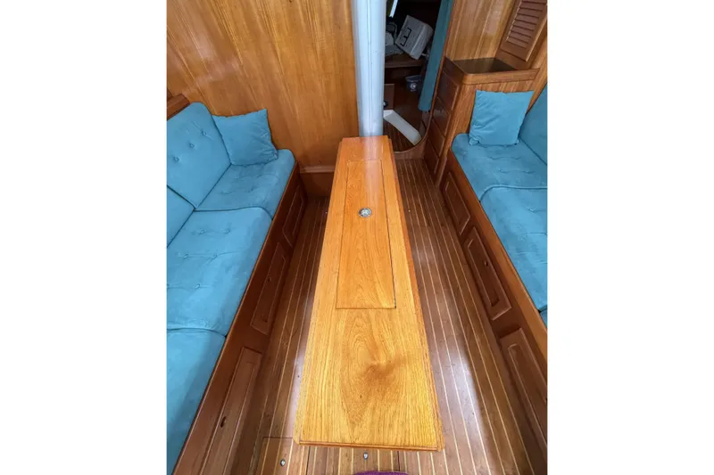 Slide: The Image of Interior of 1983 Bristol 38.8 sailboat with wooden table and blue cushioned seating. - 32