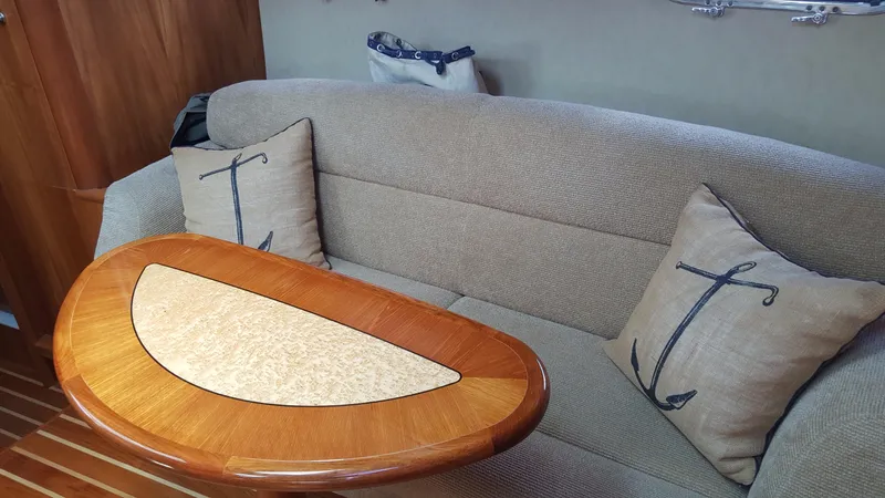 Slide: The Image of 2008 Tiara Yachts 3900 Sovran interior with beige sofa, anchor-themed pillows, and wooden table. - 28