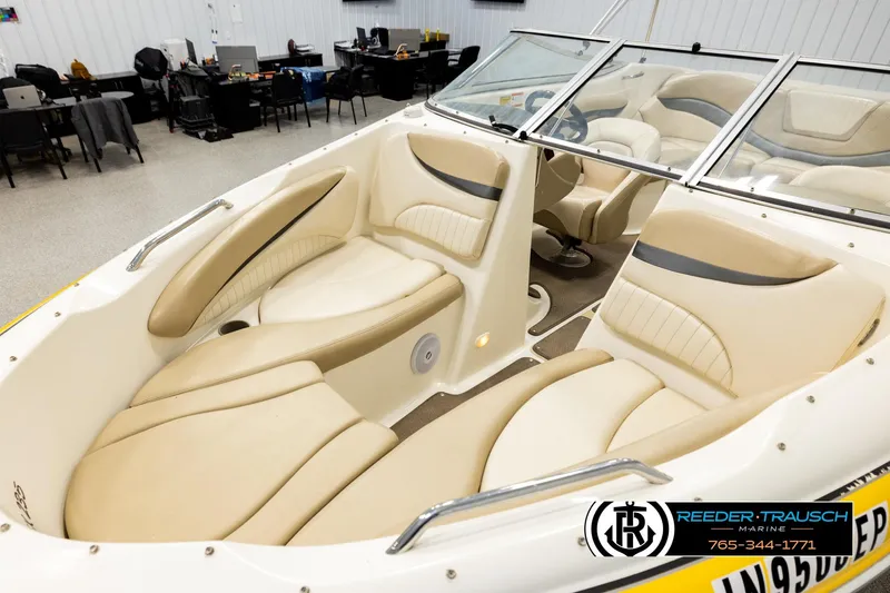 Slide: The Image of 2006 Glastron GX 235 boat interior with beige seating and windshield in showroom. - 10
