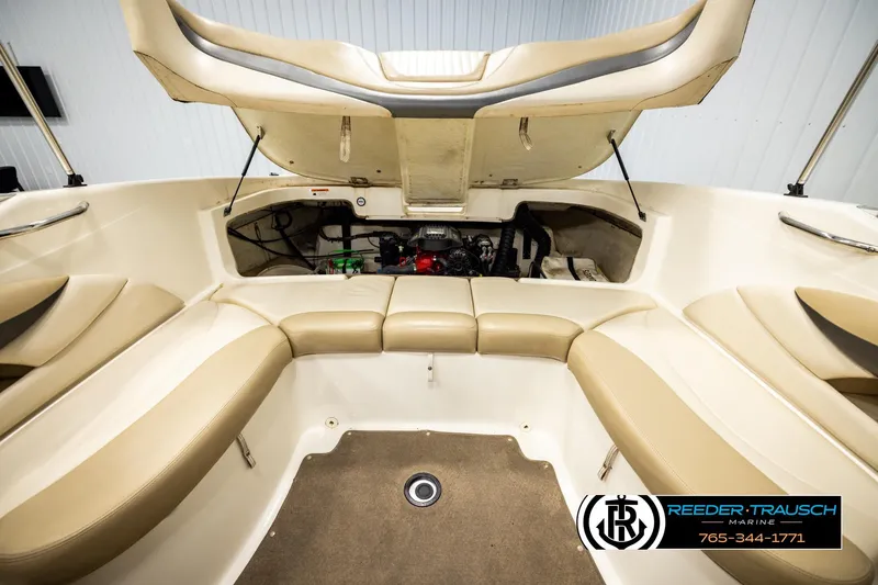 Slide: The Image of 2006 Glastron GX 235 boat interior with open engine compartment, beige seating, and carpeted floor. - 23