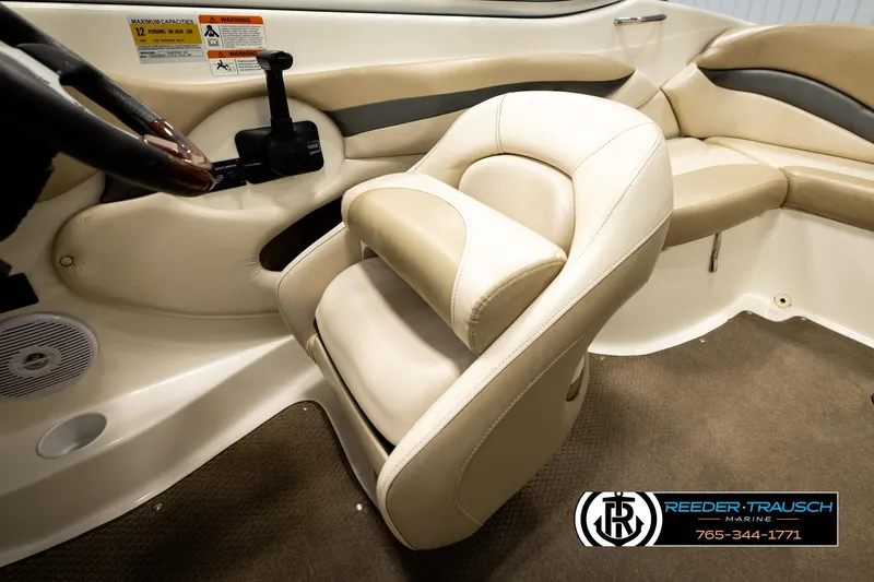 Slide: The Image of Interior of a 2006 Glastron GX 235 boat featuring beige seating and steering controls. - 27