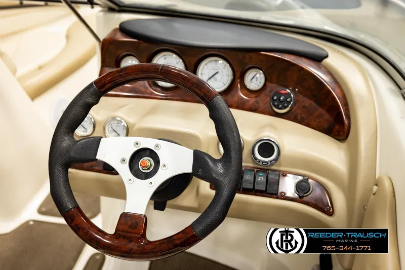 Slide: The Image of 2006 Glastron GX 235 boat dashboard with wood accents and steering wheel. - 28