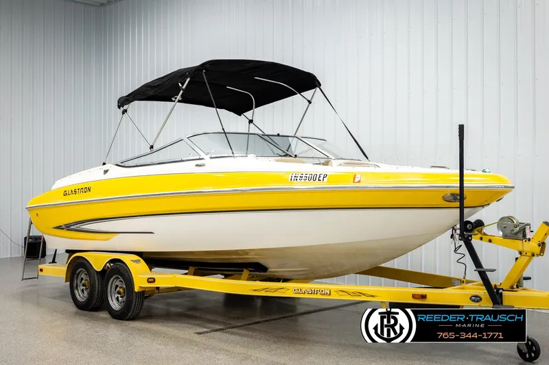 Slide: The Image of 2006 Glastron GX 235 boat with yellow accents on a trailer in a showroom. - 3