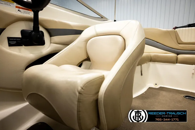 Slide: The Image of Interior of a 2006 Glastron GX 235 boat featuring beige seating and steering controls. - 36