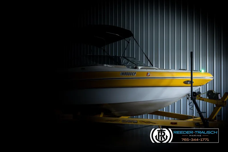 Slide: The Image of 2006 Glastron GX 235 boat in dimly lit storage, Reeder-Trausch Marine logo visible. - 4