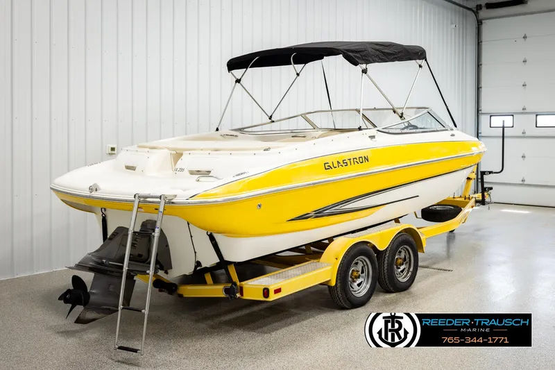 Slide: The Image of 2006 Glastron GX 235 boat in a garage, yellow and white design, on a trailer. - 6