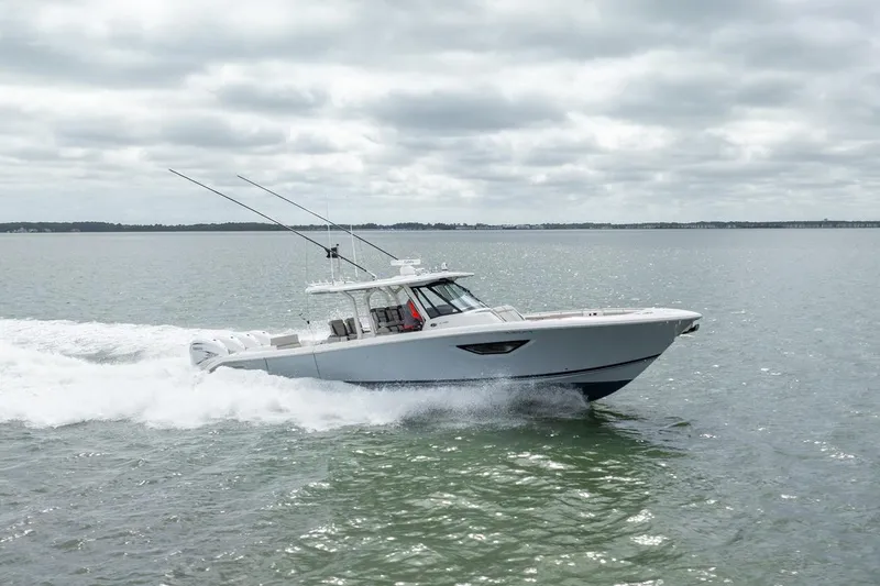 Slide: The Image of 2023 Pursuit S 428 Sport boat cruising on open water under cloudy skies. - 2
