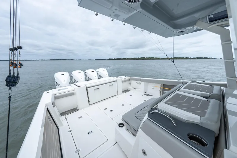 Slide: The Image of 2023 Pursuit S 428 Sport boat deck with seating and four engines on a calm sea. - 27