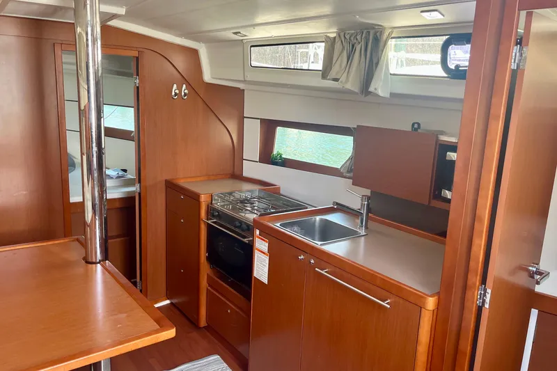 Slide: The Image of Interior of 2016 Beneteau Oceanis 38.1 yacht, featuring a modern kitchen and wood finish. - 14