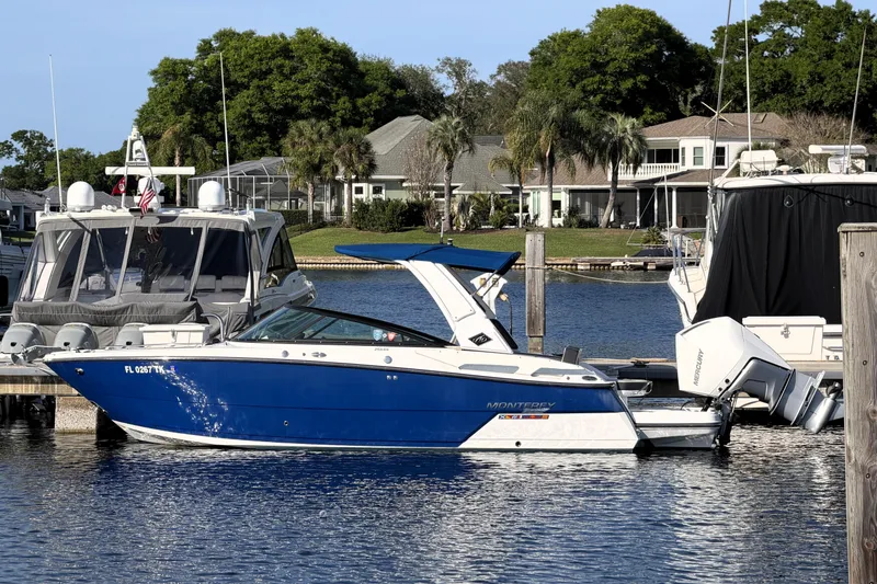 The Image of 2022 Monterey 255SS Super Sport boat docked in a marina, surrounded by trees and houses. - 0