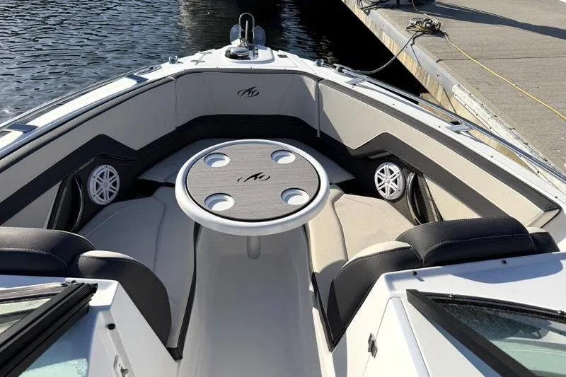 Slide: The Image of 2022 Monterey 255SS Super Sport boat interior with seating and table, docked by water. - 13