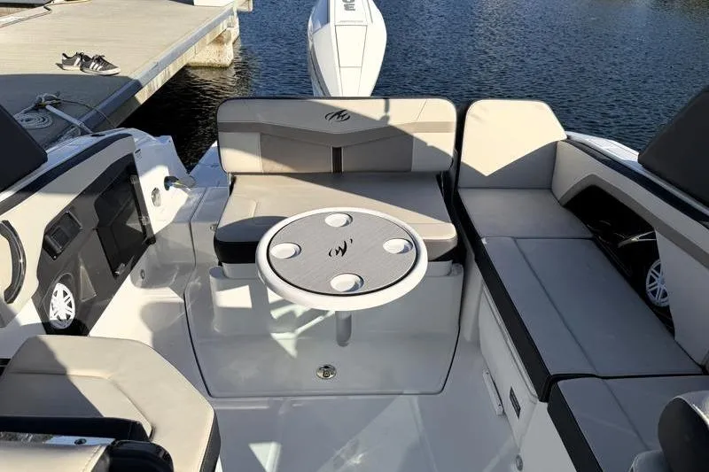 Slide: The Image of 2022 Monterey 255SS Super Sport boat interior with seating and table, docked by the water. - 34