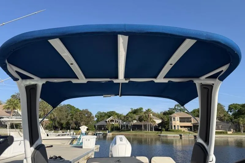 Slide: The Image of 2022 Monterey 255SS Super Sport boat with blue canopy docked by waterfront homes. - 51