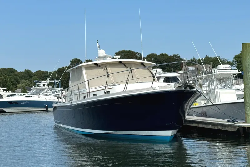 Slide: The Image of 2009 Grand Banks 45 Eastbay SX yacht docked in a marina, featuring a sleek blue hull. - 2