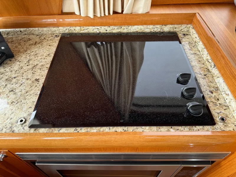 Slide: The Image of Stovetop on 2009 Grand Banks 45 Eastbay SX yacht, granite countertop, wooden cabinetry. - 23