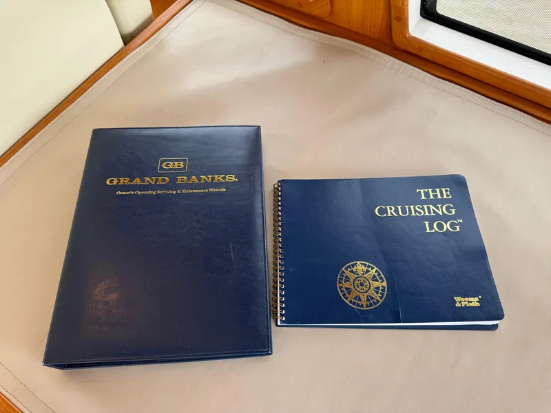 Slide: The Image of Blue Grand Banks manual and cruising logbook on a boat's interior surface. - 28