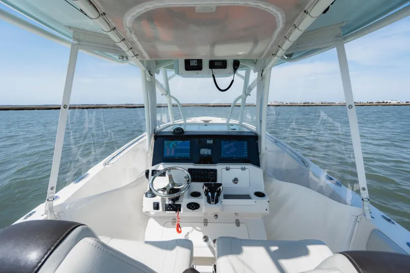 Slide: The Image of 2023 Sailfish 290 CC boat cockpit with steering wheel and navigation screens on open water. - 11
