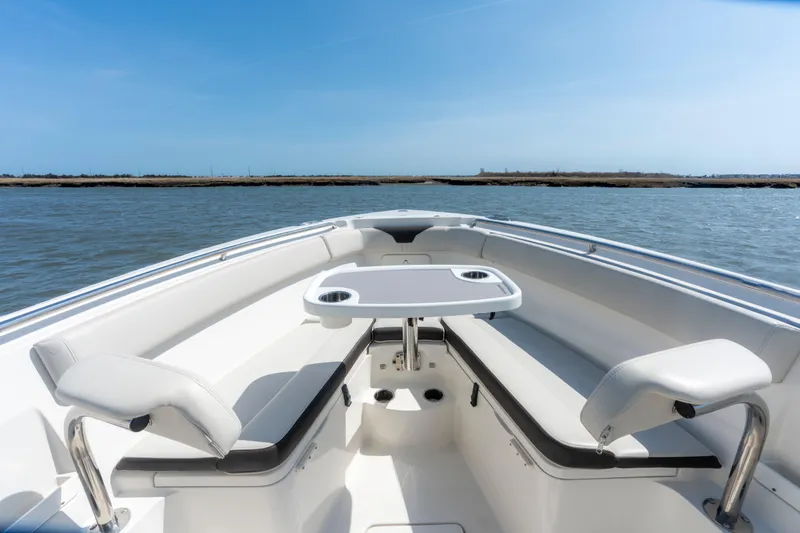 Slide: The Image of 2023 Sailfish 290 CC boat interior with seating and table on calm water. - 13