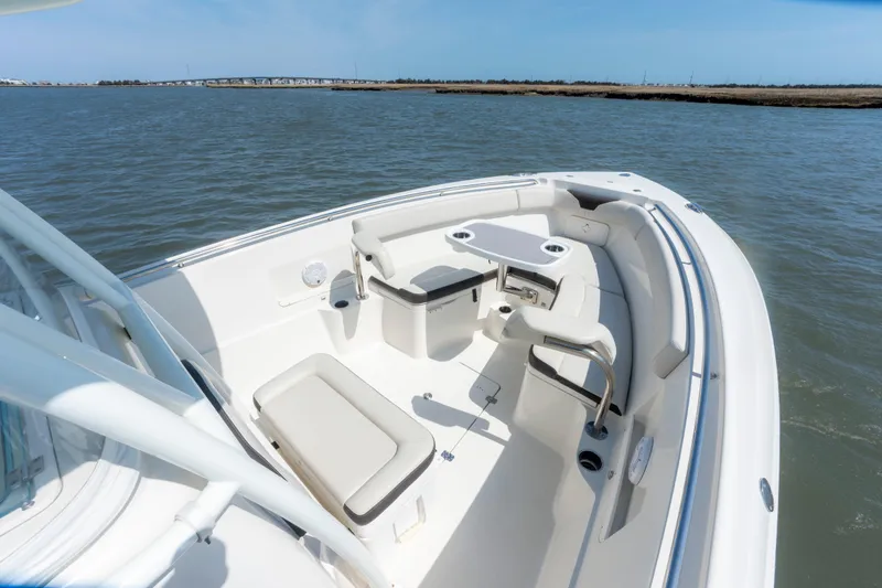 Slide: The Image of 2023 Sailfish 290 CC boat interior with seating and table on calm water. - 14