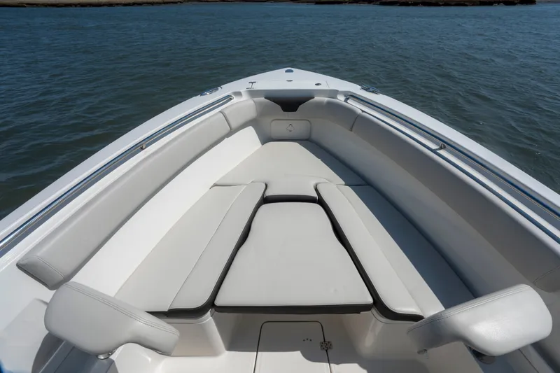 Slide: The Image of 2023 Sailfish 290 CC boat interior with cushioned seating on calm water. - 15