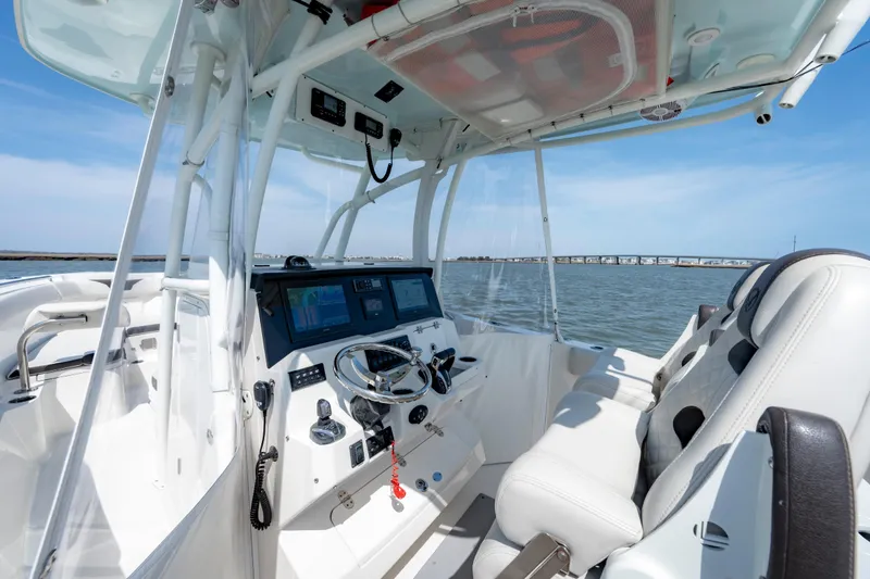 Slide: The Image of 2023 Sailfish 290 CC boat cockpit with modern controls and seating on open water. - 9