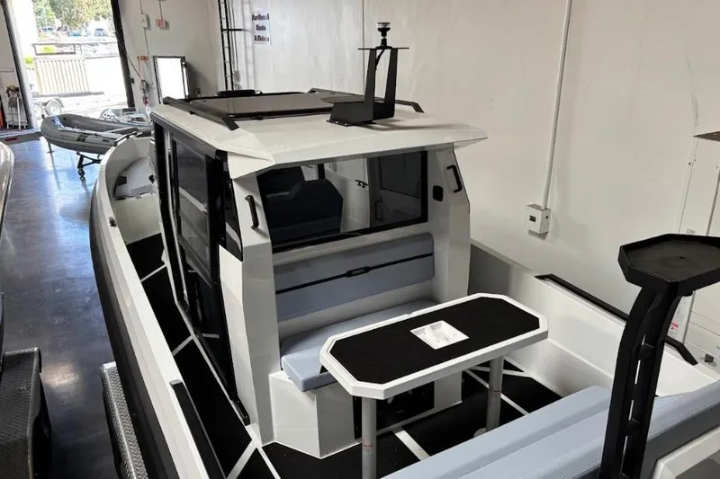 Slide: The Image of 2026 Iron 907 Coupe boat interior with seating and table in showroom. - 11