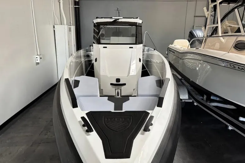 Slide: The Image of 2026 Iron 907 Coupe boat in showroom, sleek design, white and black color scheme. - 7