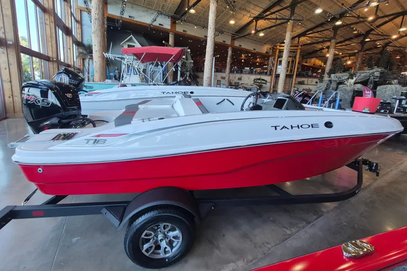 The Image of 2026 Tahoe T18 boat in showroom, featuring sleek red and white design on trailer. - 0