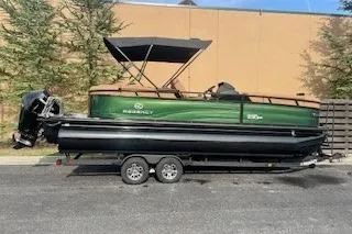 The Image of 2026 Regency 230 DL pontoon boat on trailer, green and black design. - 0