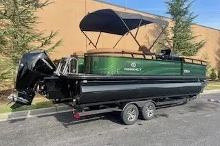 Slide: The Image of 2026 Regency 230 DL pontoon boat on trailer, featuring green and black design with canopy. - 2