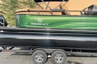 Slide: The Image of 2026 Regency 230 DL pontoon boat on trailer, featuring sleek green and black design. - 3