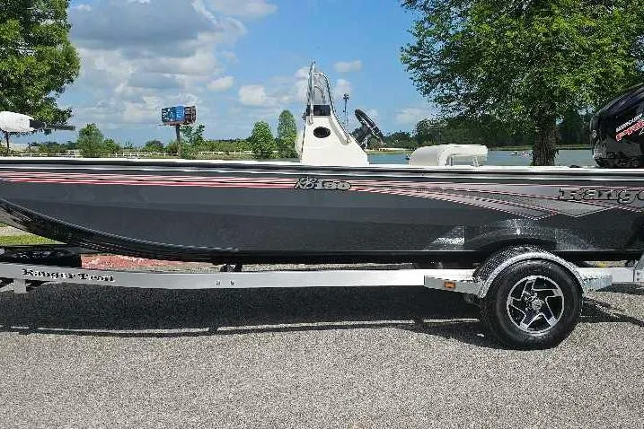 The Image of 2026 Ranger RB190 boat on trailer, parked near a scenic lake with trees and clouds. - 0