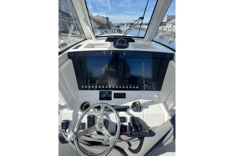 Slide: The Image of 2022 Regulator 28 Forward Seating boat dashboard with dual screens and steering wheel. - 6