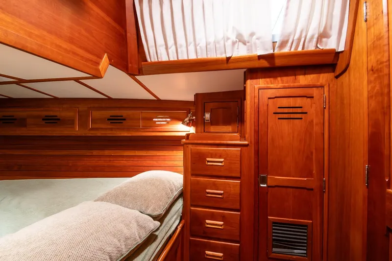 Slide: The Image of Hinckley Sou'wester 51 yacht interior, 1989, featuring wooden cabinetry and cozy bedding. - 44