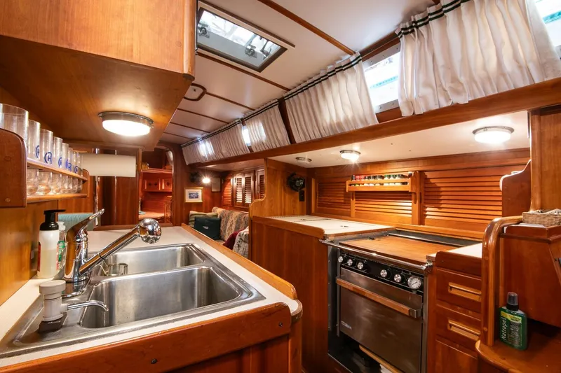 Slide: The Image of Interior of 1989 Hinckley Sou'wester 51 yacht, featuring a well-equipped wooden galley kitchen. - 53