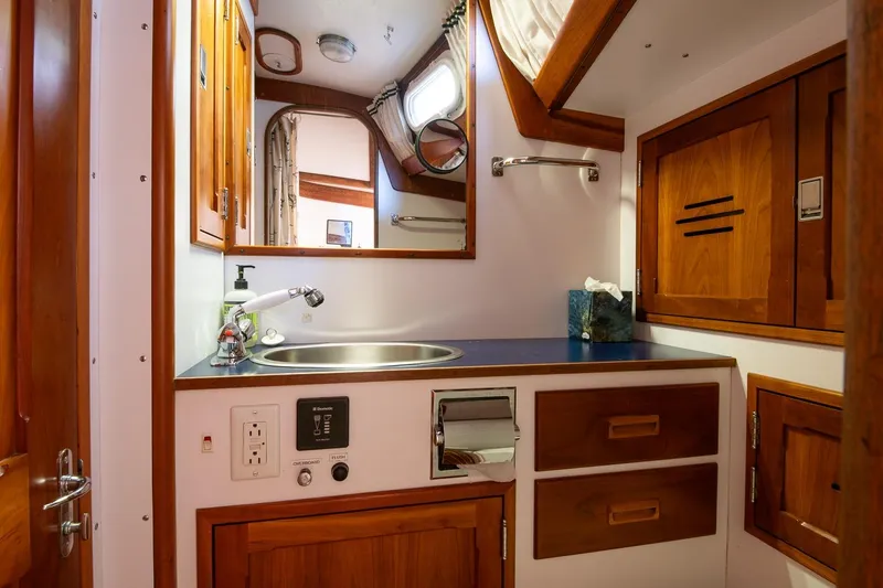 Slide: The Image of Hinckley Sou'wester 51 yacht bathroom, featuring wooden cabinetry and a sleek sink, 1989 model. - 65