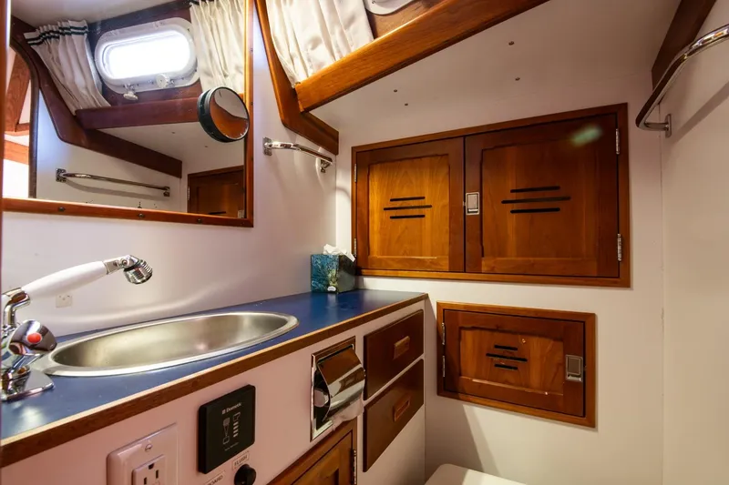 Slide: The Image of Hinckley Sou'wester 51 yacht bathroom, featuring wooden cabinets and a sleek sink, 1989 model. - 66