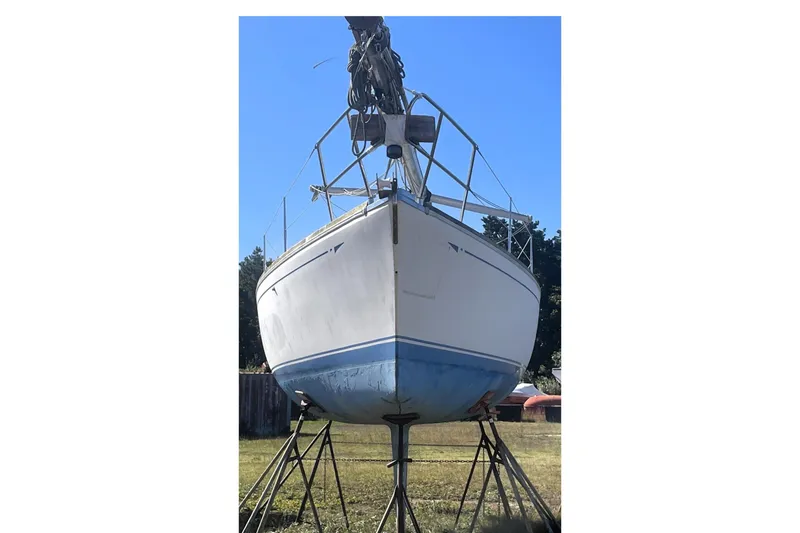 The Image of 1986 CAL 28 sailboat on stands, displayed outdoors under clear blue sky. - 0