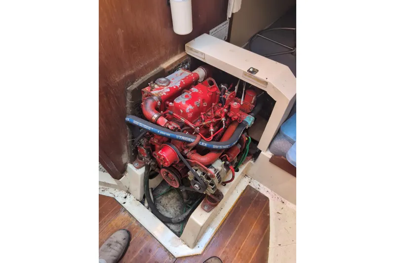 Slide: The Image of Red engine inside a 1986 CAL 28 sailboat, showing detailed components and hoses. - 11
