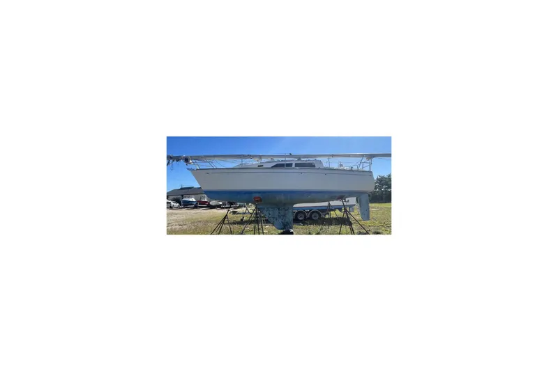 Slide: The Image of 1986 CAL 28 sailboat on stands in a grassy yard under clear blue sky. - 2