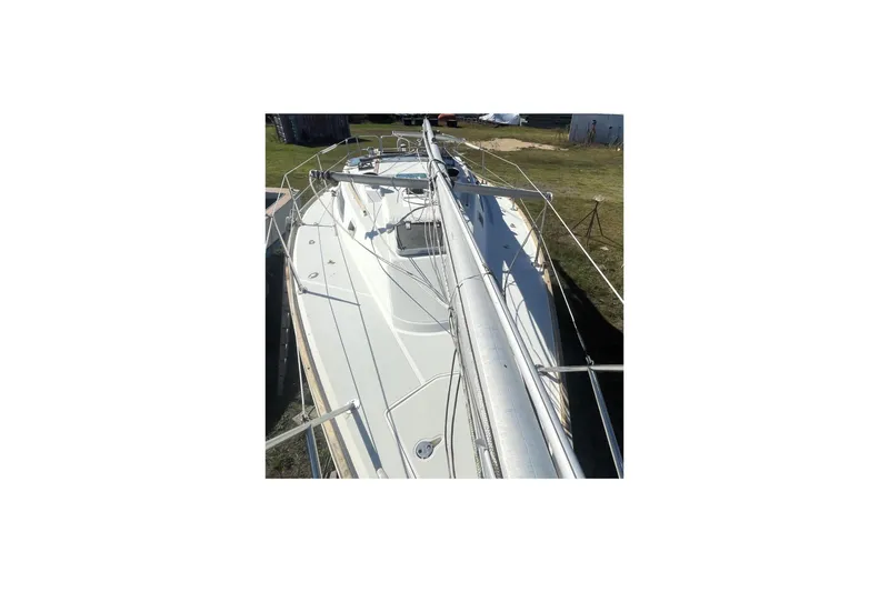 Slide: The Image of 1986 CAL 28 sailboat on land, showcasing deck and mast in a grassy area. - 3