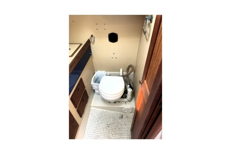 Slide: The Image of Compact marine bathroom in a 1986 CAL 28 sailboat, featuring a toilet and storage. - 9